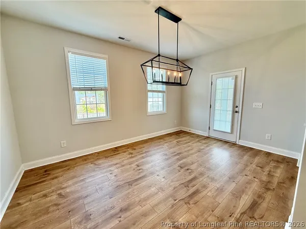 a view of empty room with wooden floor and window