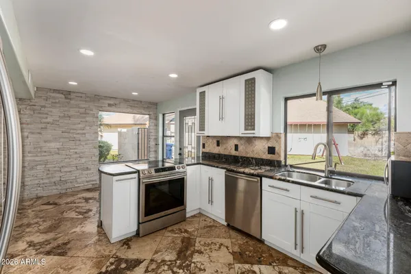 a kitchen with stainless steel appliances granite countertop a stove a sink and a refrigerator