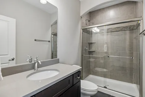 a bathroom with a granite countertop sink toilet a mirror and shower