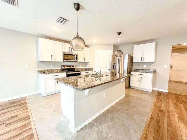 a kitchen with stainless steel appliances granite countertop a stove top oven a sink dishwasher and a refrigerator