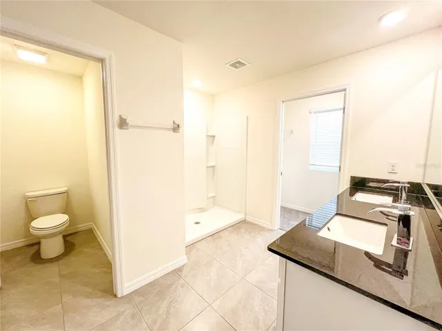 a bathroom with a granite countertop sink a toilet and a shower