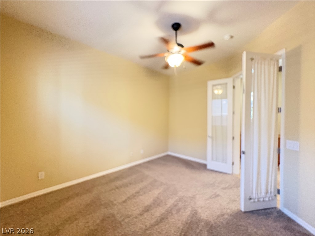 10 Caprington Road Henderson, NV 89052 - Photo 21 of 44 A versatile room awaits, offering plush carpeting and a gentle ceiling fan for comfort.
