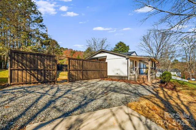 a view of backyard with large trees and wooden fence