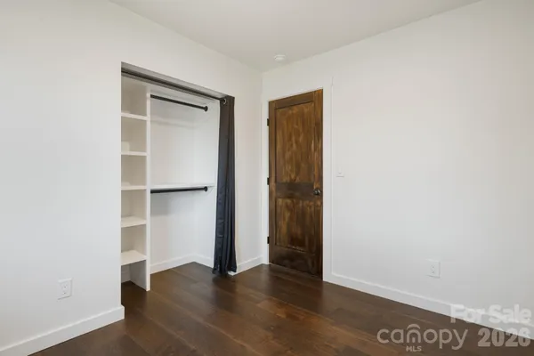 a view of an empty room with closet and a window