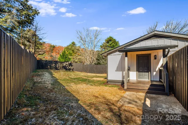 a view of a wooden house with a large window and potted plants