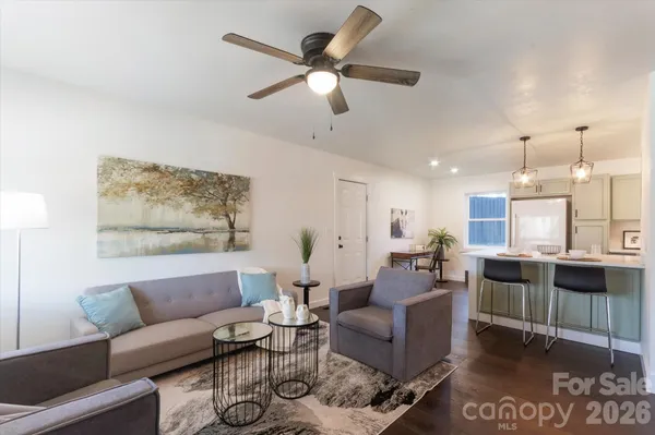 a living room with furniture kitchen view and a large window