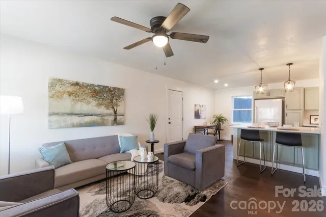 a living room with furniture kitchen view and a large window