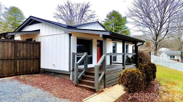 a view of a house with wooden walls and floor to ceiling window and wooden fence