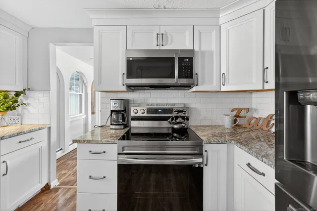 a kitchen with stainless steel appliances granite countertop a stove a microwave and a white cabinets