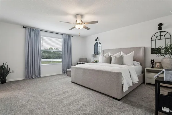 a spacious bedroom with a bed a chandelier and windows