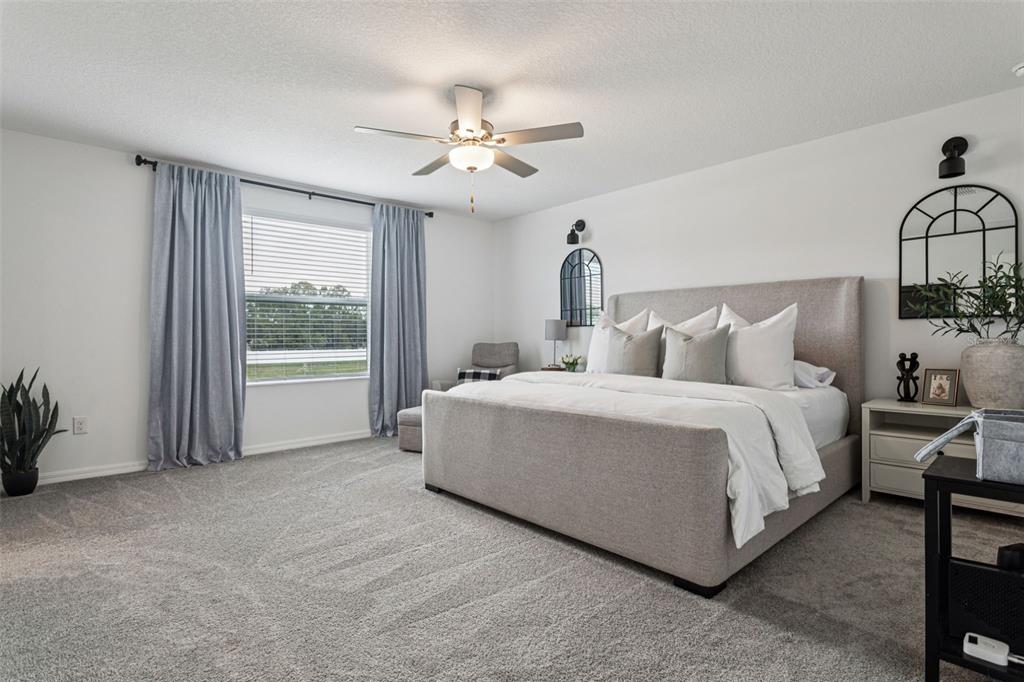 11693 Lavender Loop Spring Hill Spring Hill, FL 34609 - Photo 18 of 34 a spacious bedroom with a bed a chandelier and windows