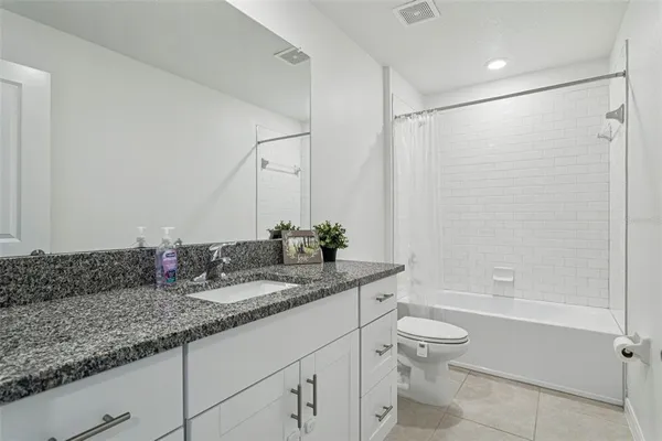 a bathroom with a granite countertop sink a toilet and shower