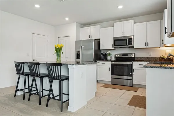 a kitchen with stainless steel appliances kitchen island granite countertop a stove a sink and a refrigerator