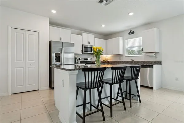 a kitchen with stainless steel appliances granite countertop a table chairs microwave and sink