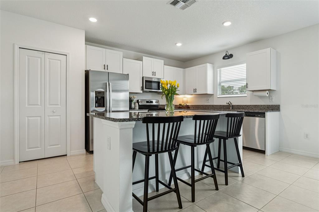 11693 Lavender Loop Spring Hill Spring Hill, FL 34609 - Photo 6 of 34 a kitchen with stainless steel appliances granite countertop a table chairs microwave and sink