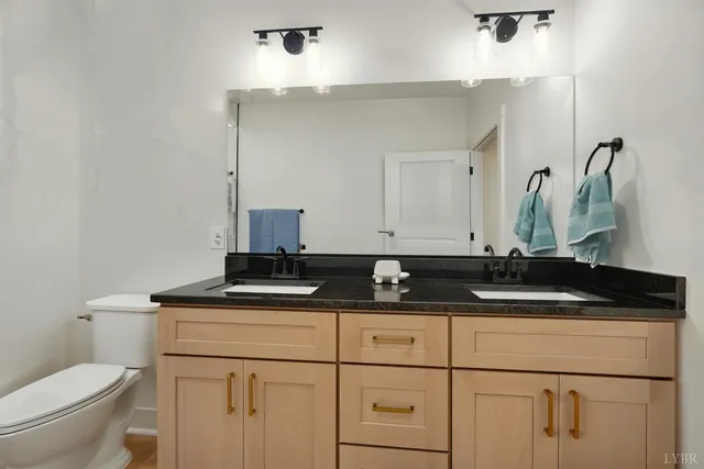 a bathroom with a granite countertop sink a toilet and a mirror