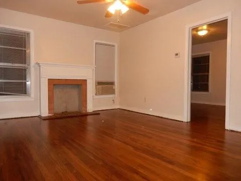 an empty room with wooden floor fireplace and windows