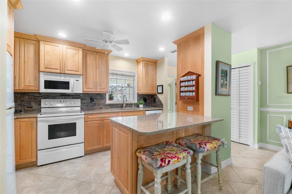 3533 Tree Line Court, Unit 13 Sarasota, FL 34231 - Photo 10 of 38 a kitchen with stainless steel appliances kitchen island granite countertop a stove a sink and a microwave