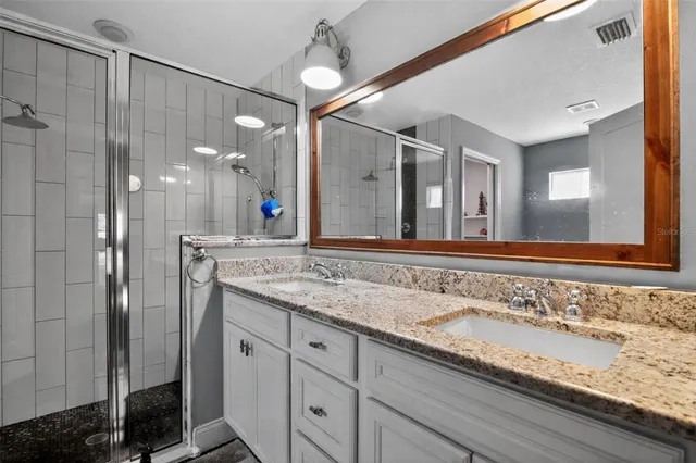 a bathroom with a granite countertop sink a large mirror and a shower