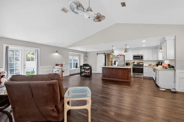 a living room with furniture kitchen view and a wooden floor