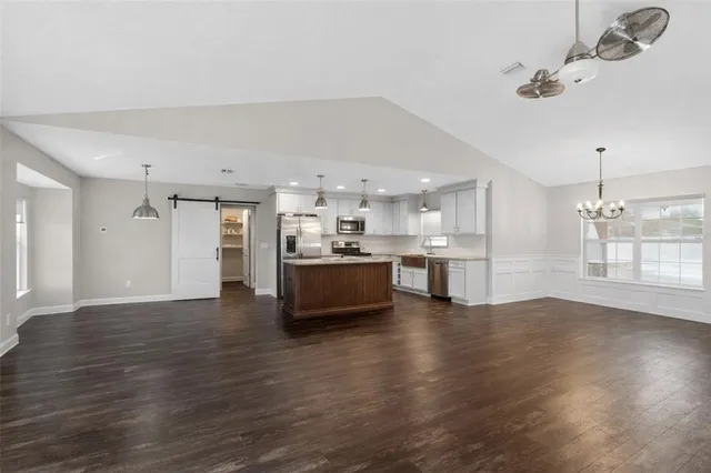 a view of a kitchen with kitchen island a sink wooden floor and a refrigerator