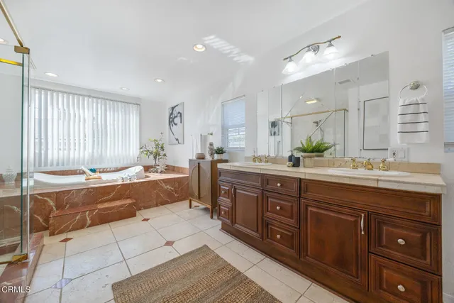 a spacious bathroom with a granite countertop double vanity sink a mirror and a bathtub