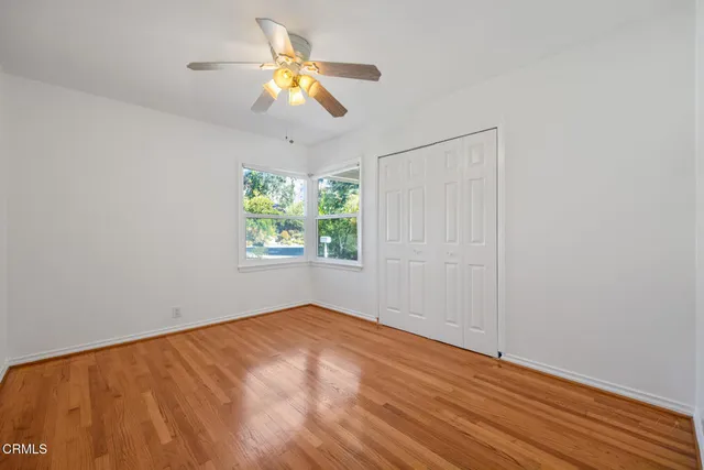 an empty room with a window and ceiling fan