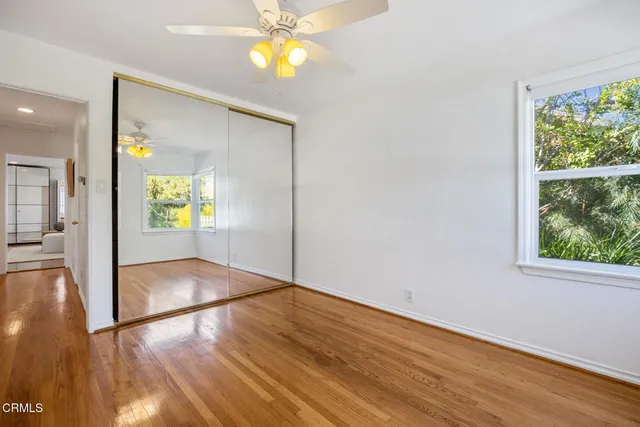 a view of empty room with wooden floor and fan