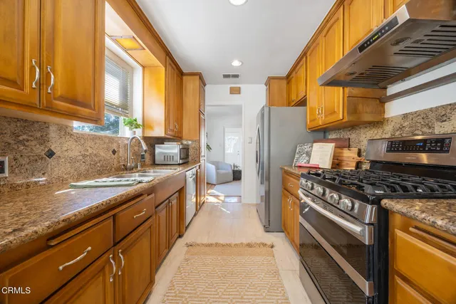 a kitchen with stainless steel appliances granite countertop a stove a sink and a refrigerator