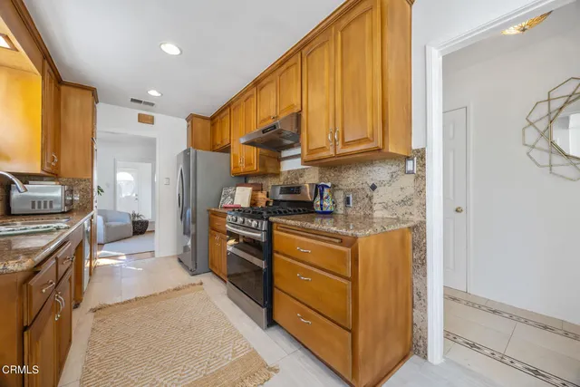 a kitchen with stainless steel appliances granite countertop a stove a sink a refrigerator and a microwave