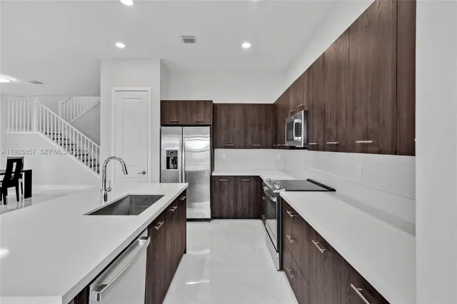 a large white kitchen with stainless steel appliances kitchen island a large counter top a stove and a sink