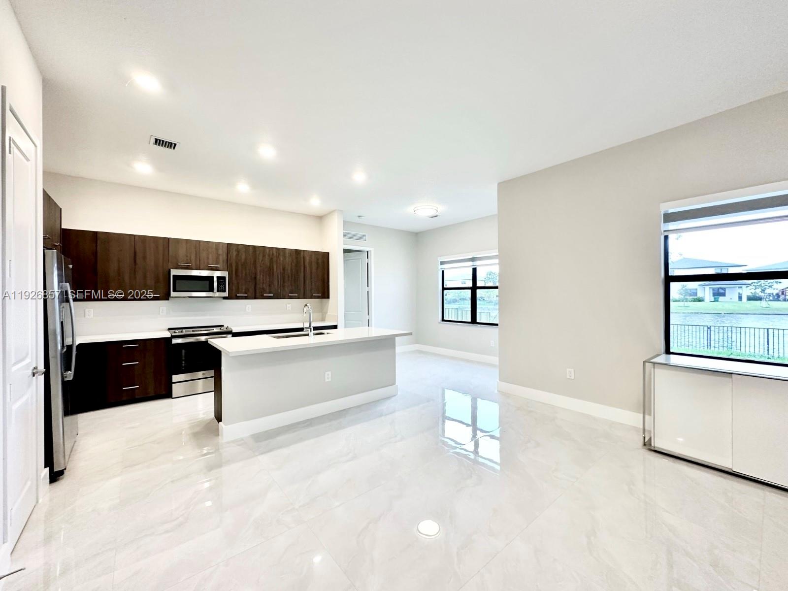 4276 Southwest 173rd Avenue Miramar, FL 33029 - Photo 16 of 58 a large white kitchen with stainless steel appliances kitchen island a large counter top a stove and a sink