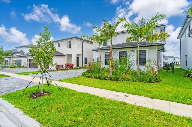 a front view of a house with a yard and potted plants
