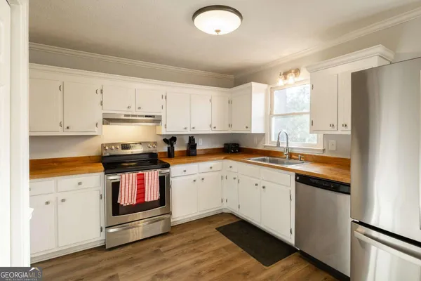 a kitchen with stainless steel appliances granite countertop a stove a sink and white cabinets