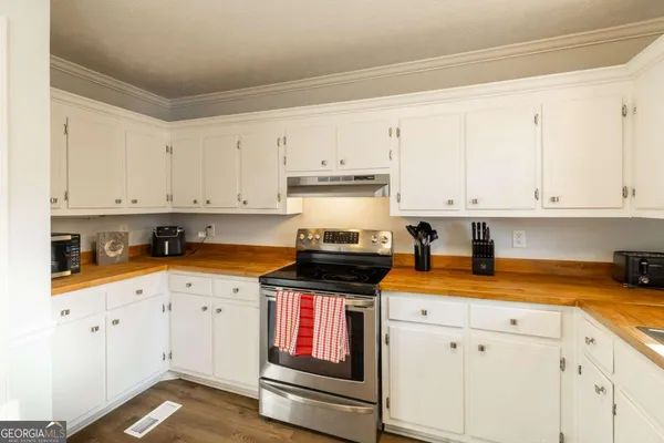 a kitchen with stainless steel appliances granite countertop a stove a sink and white cabinets