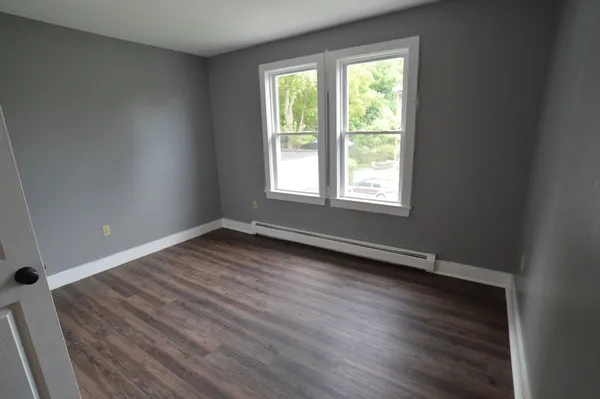 a view of an empty room with wooden floor and a window