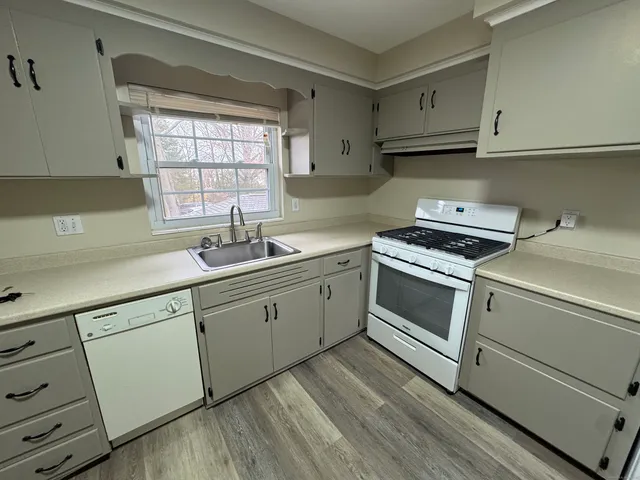 a kitchen with cabinets appliances a sink and a window