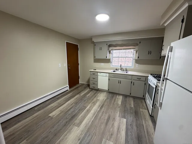 a kitchen with a sink a refrigerator a window and cabinets