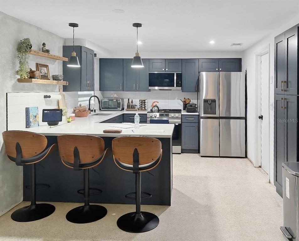 3922 Darlington Road Holiday, FL 34691 - Photo 15 of 30 a kitchen with stainless steel appliances granite countertop a sink a stove a refrigerator and chairs