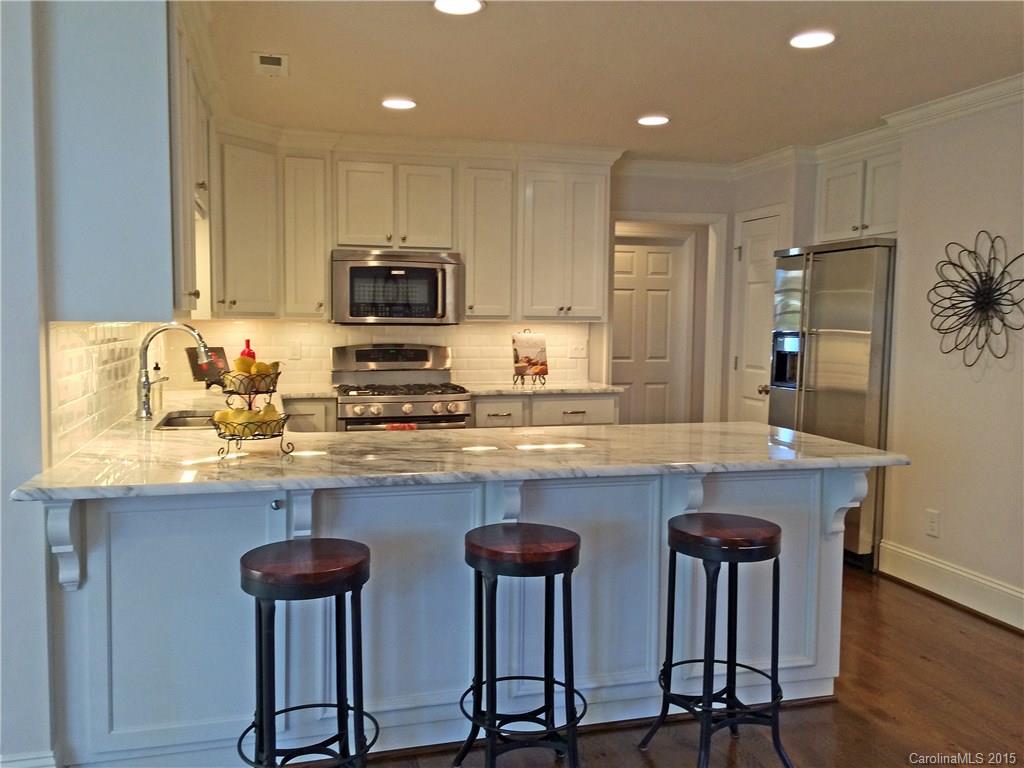 3003 Clarendon Road, Unit A Charlotte, NC 28211 - Photo 6 of 13 a kitchen with cabinets a sink and chairs