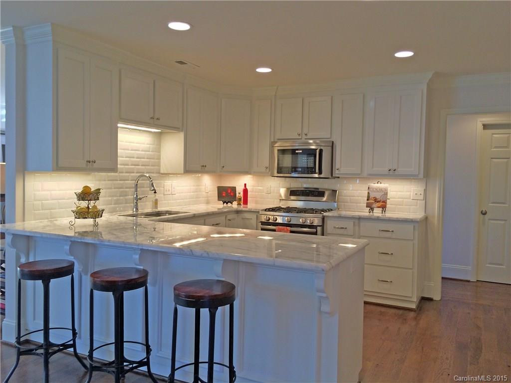 3003 Clarendon Road, Unit A Charlotte, NC 28211 - Photo 7 of 13 a kitchen with kitchen island granite countertop wooden cabinets and a granite counter tops with a stove