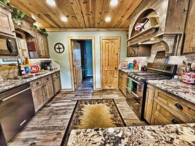 a kitchen with stainless steel appliances granite countertop a stove a sink dishwasher and granite countertops with a flat screen tv
