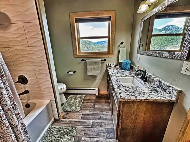a bathroom with a granite countertop sink a mirror and shower