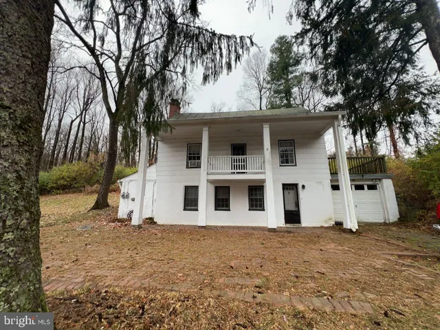 a view of a white house with a large tree