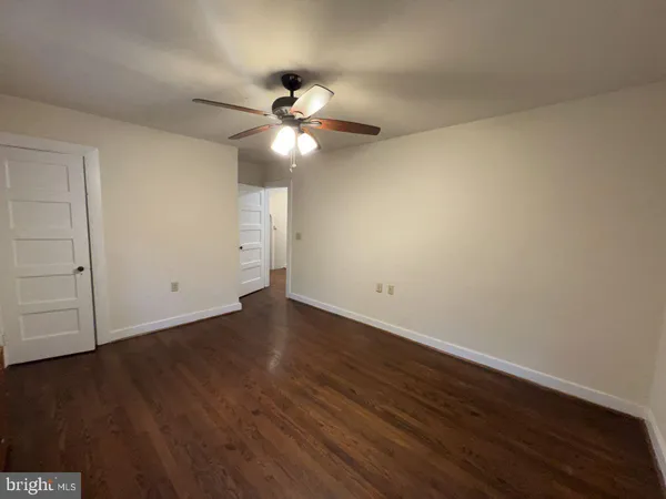 an empty room with wooden floor and fan