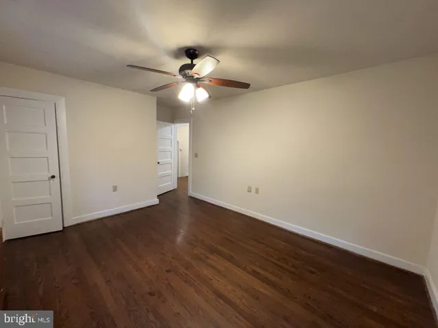an empty room with wooden floor and fan