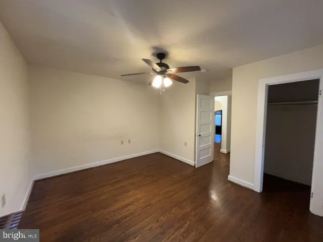 an empty room with wooden floor and ceiling fan