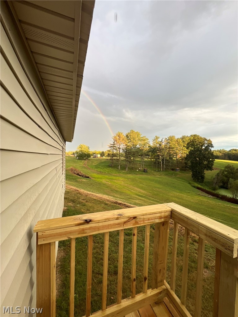 1105 Dutch Ridge Road Guysville, OH 45735 - Photo 23 of 33 Exterior balcony featuring wood railing and decking, with a backdrop of rolling green hills and mature trees