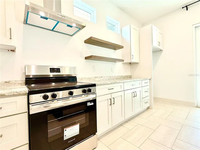 a kitchen with granite countertop a stove a sink and a microwave