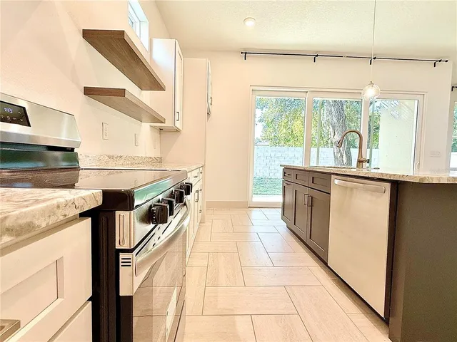 a kitchen with stainless steel appliances granite countertop a sink a stove and a wooden floors